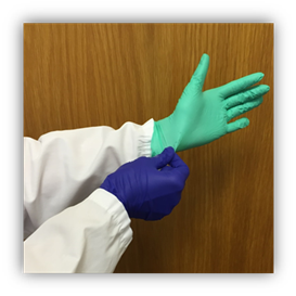  two gloved hands, with different colored gloves. The gloved right hand is pinching the base of the left hand glove at the wrist.