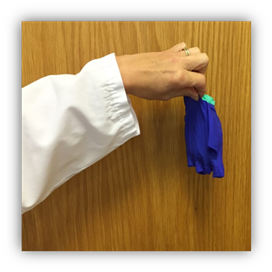 Left hand is pinching both removed gloves with the first gloved enclosed in the second.